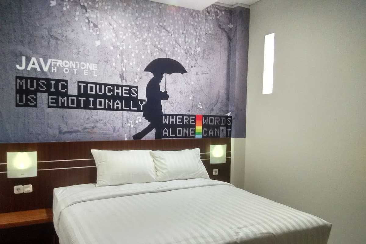 A hotel room with a bed, a headboard, and a wall with a poster.