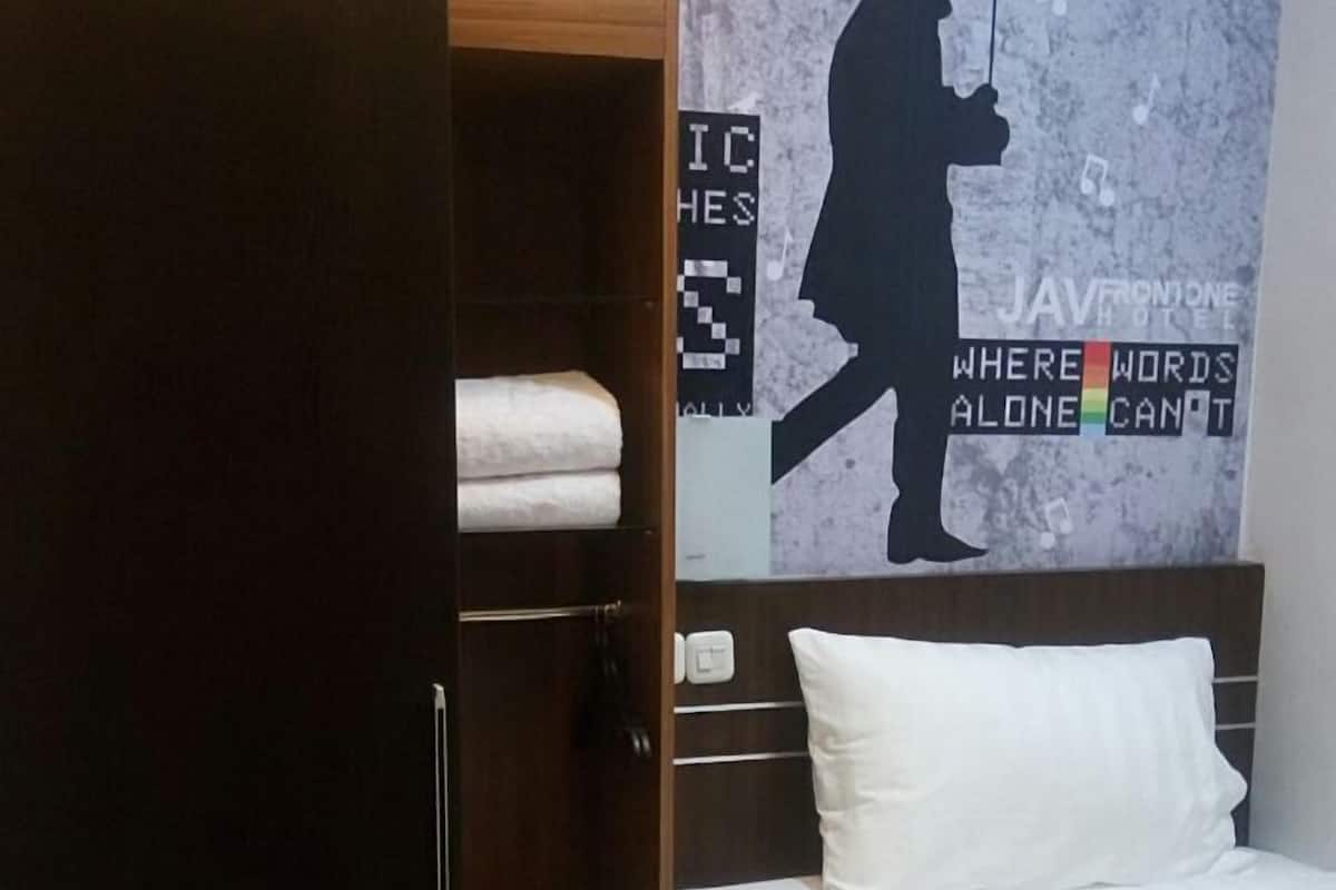 A bedroom with a bed, a wardrobe, and a wall with a music-themed mural.