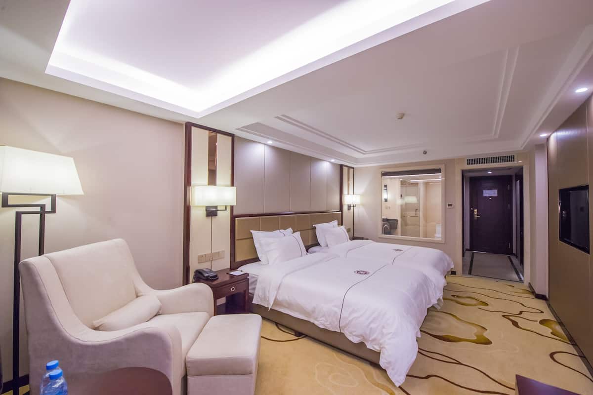 Une chambre d’hôtel avec un grand lit, une chaise, un bureau et une lampe.