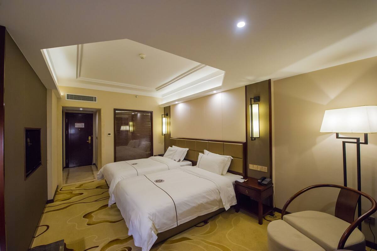 Une chambre d’hôtel avec un grand lit, des tables de chevet, une chaise et un bureau avec une lampe.