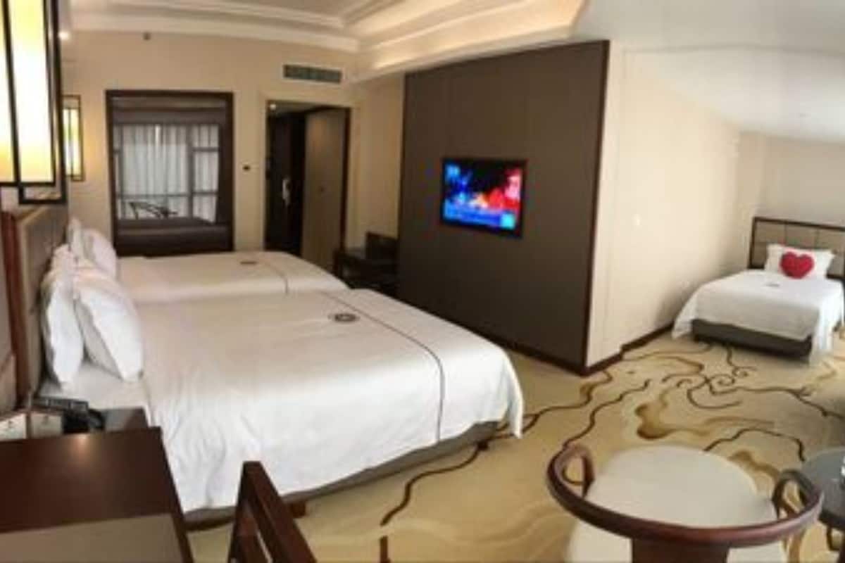 Une chambre d’hôtel avec deux lits, une télévision, un bureau et une chaise.
