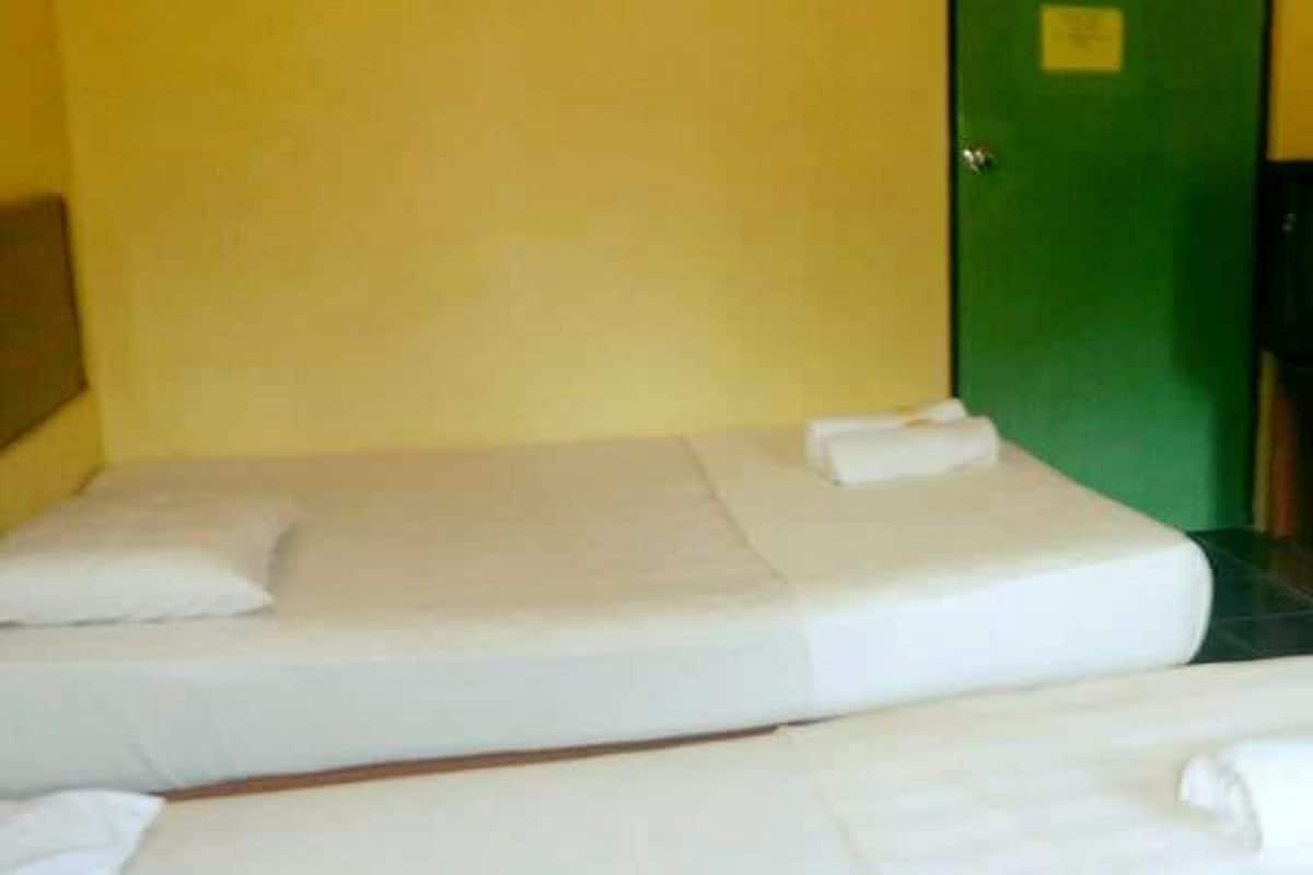 A room with two beds, a green door, and a yellow wall.