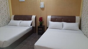 Deux lits simples avec des têtes de lit marron, une literie blanche et une petite table de chevet ornée d’une fleur rouge.