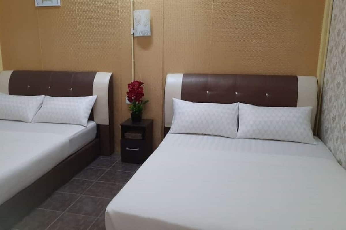 Two single beds with brown headboards, white bedding, and a small bedside table with a red flower.