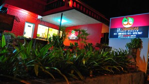 Un bâtiment à la façade rouge, doté d’un espace d’accueil et d’une enseigne indiquant « De Chempedak Guest House ».