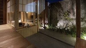 A modern bathroom with a wooden bathtub, a sink, and a glass enclosure. - Kamohan (Kyoto)