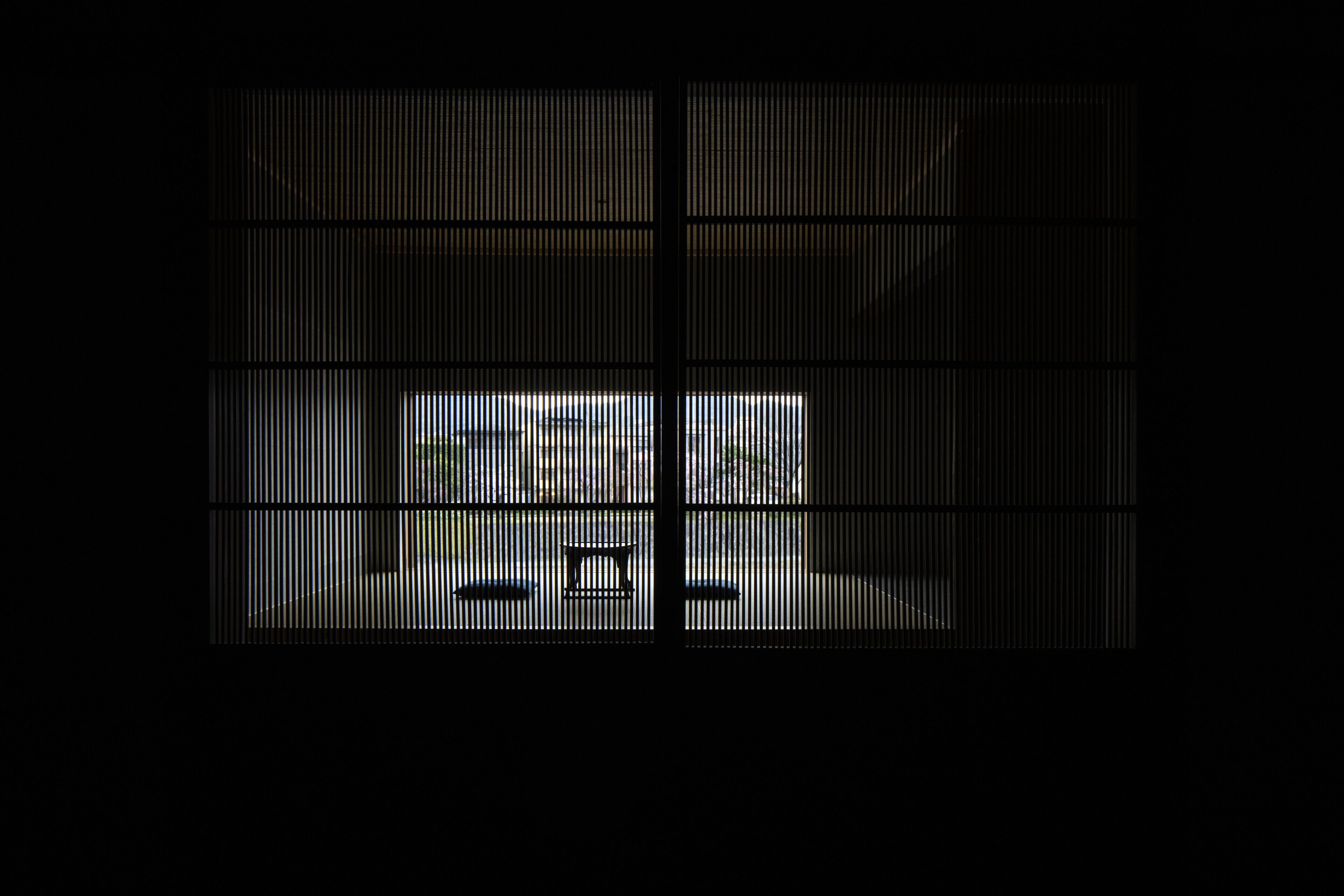 A room with a large window, a bed, and a bedside table.