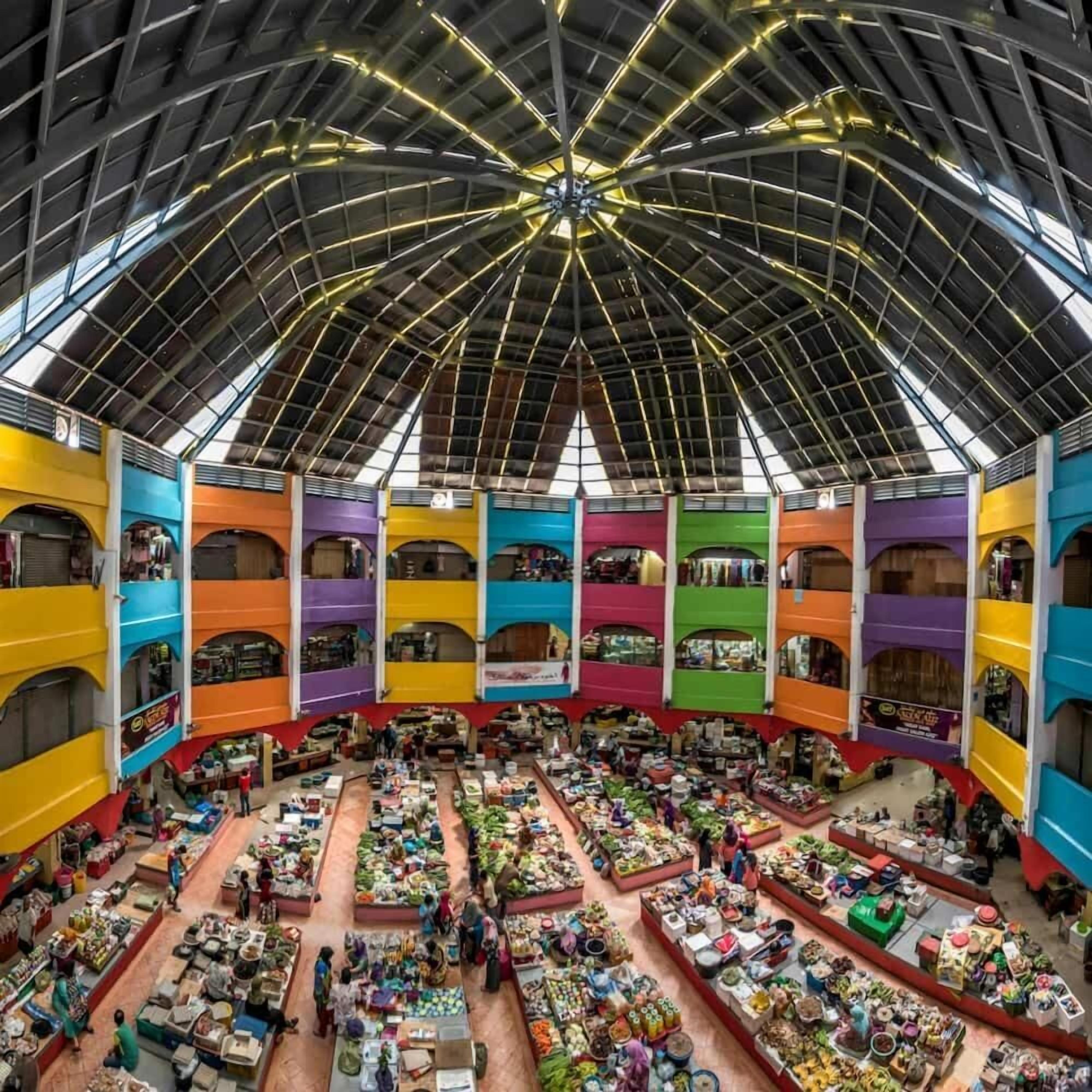 A multi-level indoor market with various stalls and shoppers.