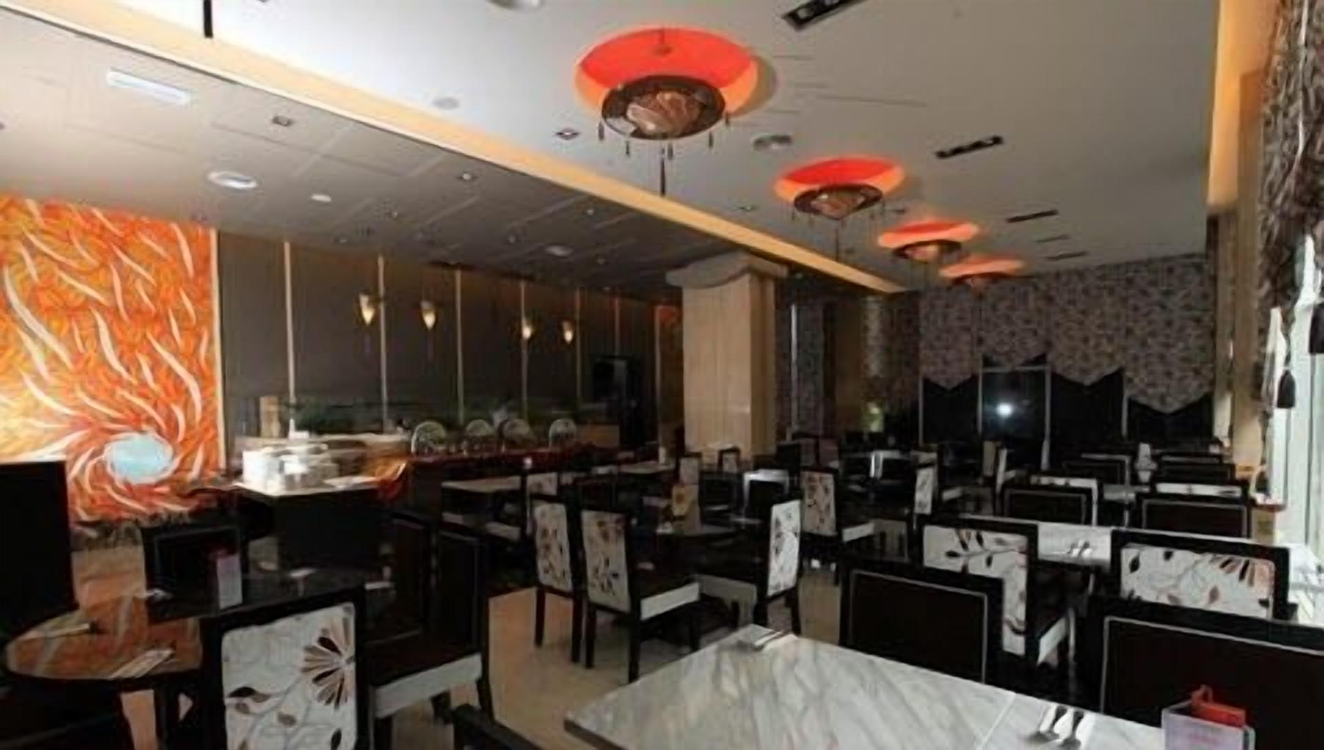 Un restaurante con un interior moderno, que cuenta con sillas de diseño blanco y negro, luces de techo rojas y una mesa de mármol.