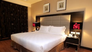 A hotel room with a large bed, two bedside tables, a headboard, and two framed pictures on the wall.