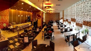 A restaurant with a long counter, multiple tables, and chairs.
