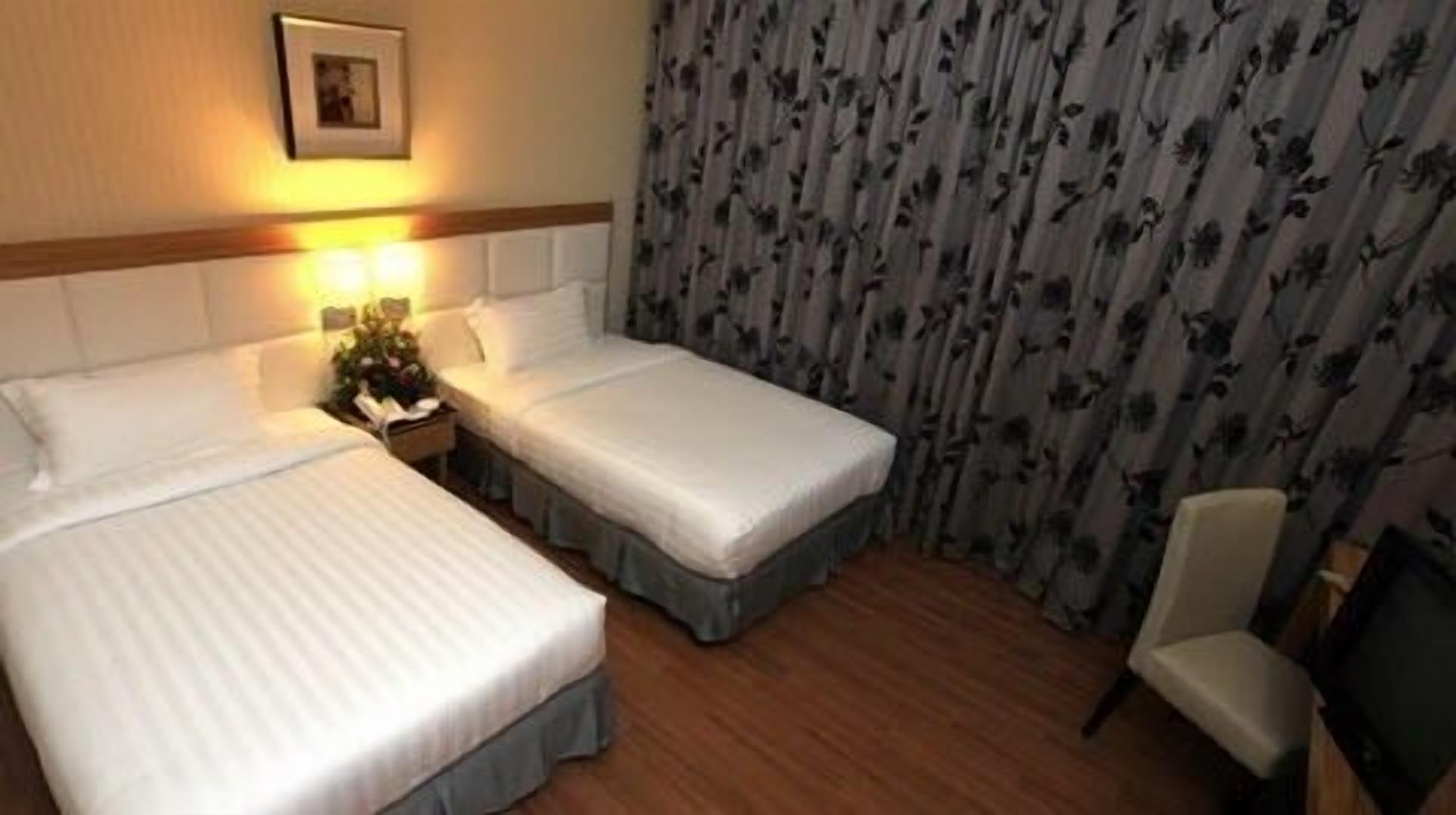 A hotel room with two beds, a chair, and a floral curtain.