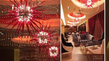 En lyxig hotellobby med elegant möblemang, en kristallkrona och en röd gardin.