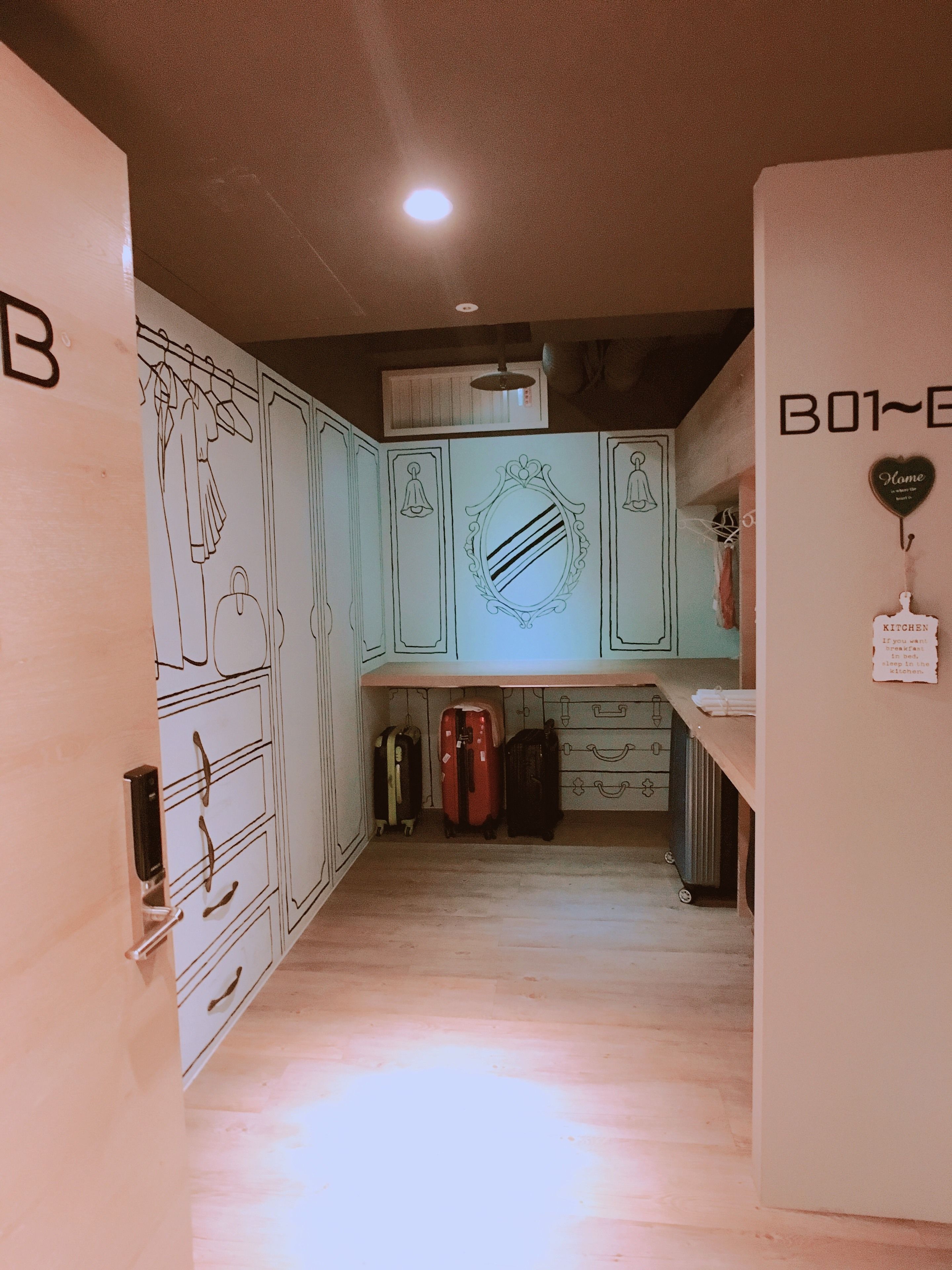 A kitchen with white cabinets, a countertop, and a hanging light fixture. There is a sign on the wall that says "Home."