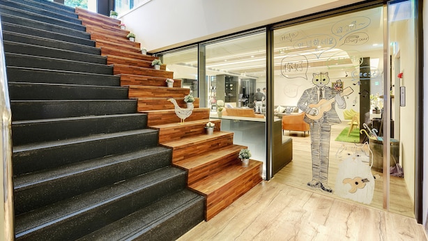 A staircase with wooden steps and black risers, leading to a glass door with a mural of a cat playing a guitar. - Taiwan Youth Hostel & Capsule Hostel (Taipei)