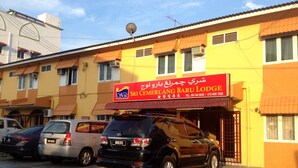 Un edificio con un letrero que dice Sri Cemerlang Baru Lodge. Hay coches estacionados en la parte delantera.