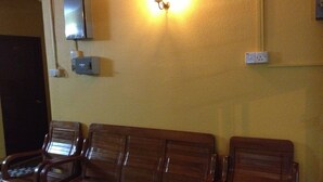 Un área de espera con bancos de madera, un televisor montado en la pared y enchufes.