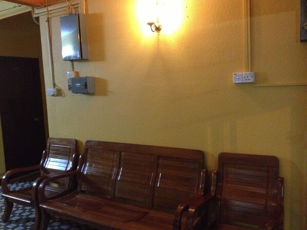 Un área de espera con bancos de madera, un televisor montado en la pared y enchufes.