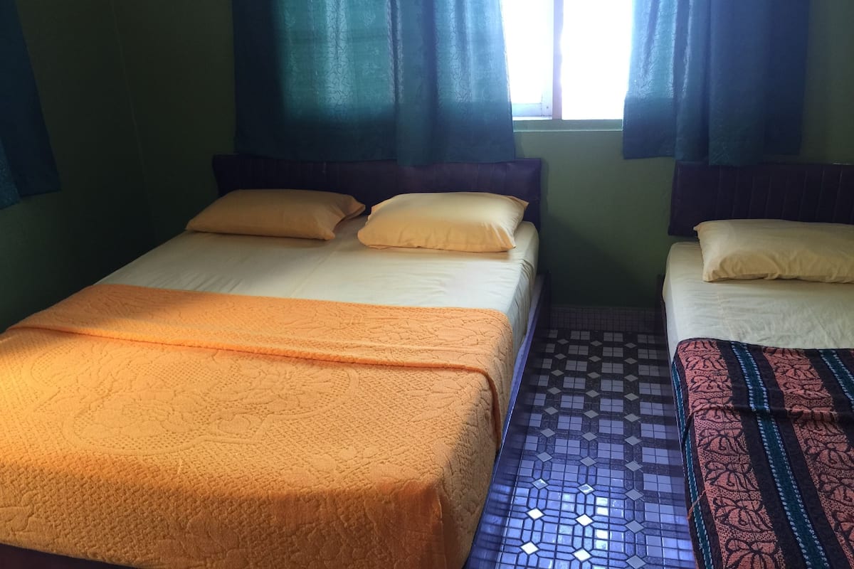 Une chambre avec deux lits, chacun recouvert d’une couvre-lit à motifs différents.