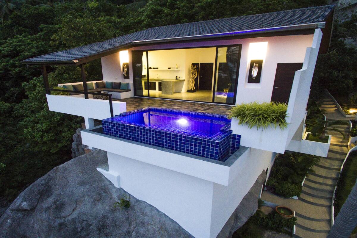 Ein modernes Haus mit Schwimmbad, Balkon und Blick auf den umliegenden Wald.
