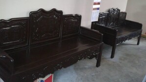 Un banco de madera oscura con intrincados grabados y una mesita auxiliar a su lado.