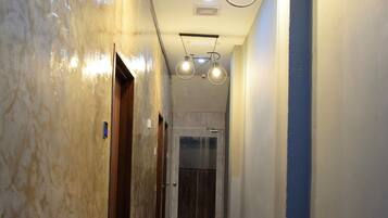 A hallway with marble walls, wooden floors, and pendant lighting.