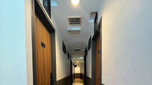 Un pasillo largo y estrecho con suelo de madera y paredes oscuras.