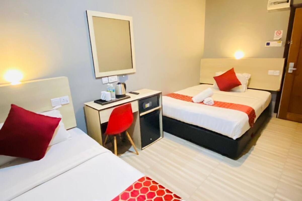 A hotel room with two beds, a desk, and a chair.