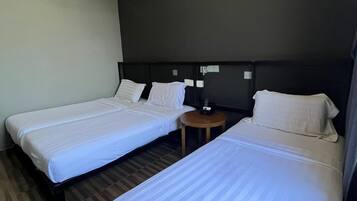 A hotel room with two single beds, a small round table, and a dark-colored headboard.