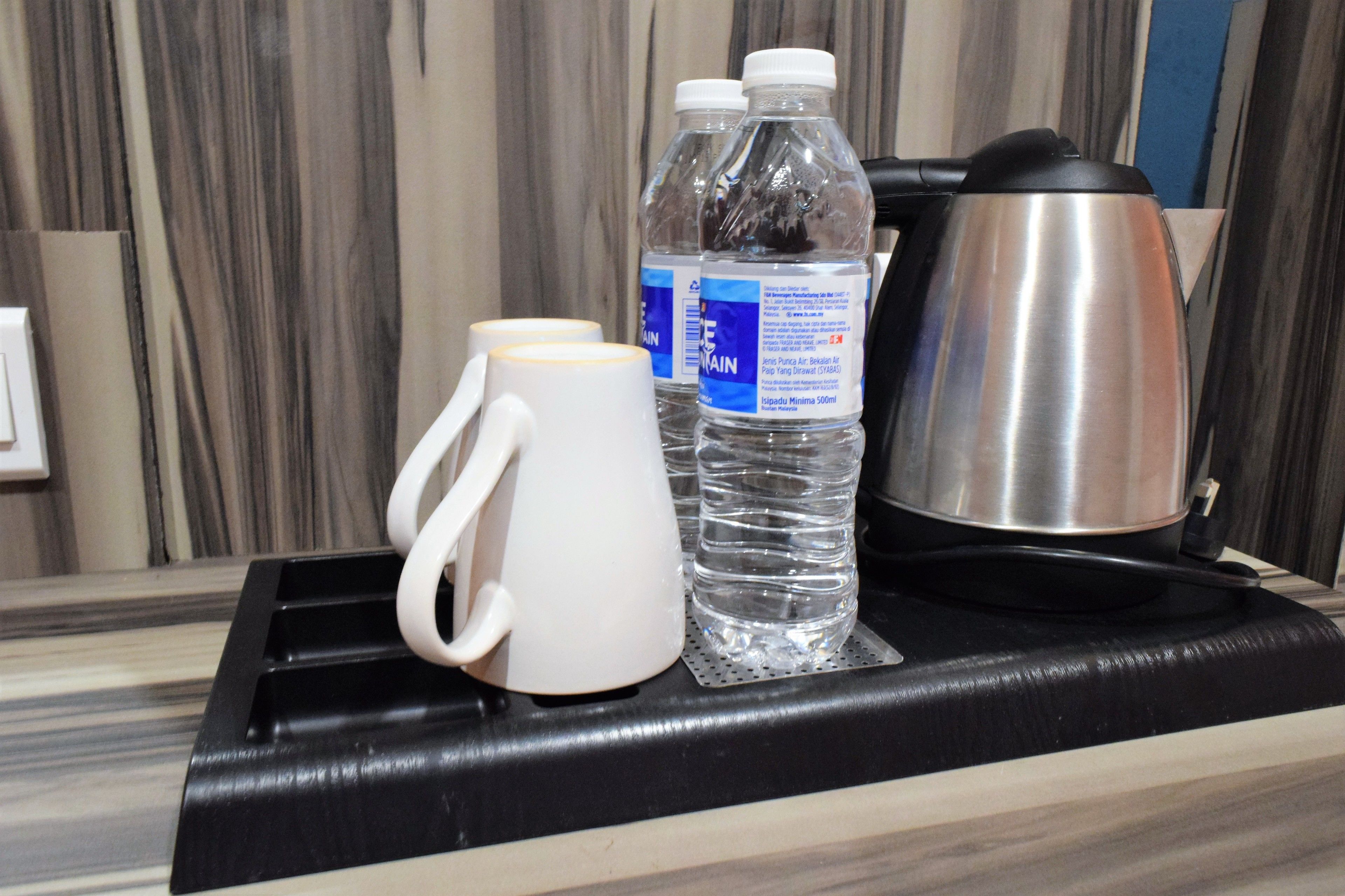 A kitchen counter with a coffee maker, two water bottles, and a white mug.