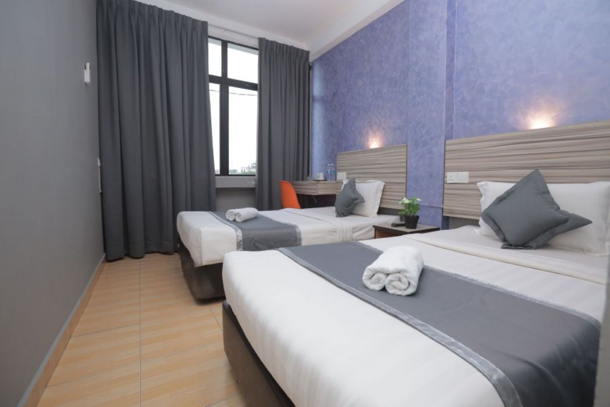 A hotel room with two beds, a desk, and a window with curtains.