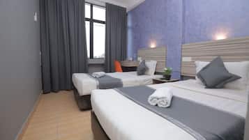 A hotel room with two beds, a desk, and a window with curtains.