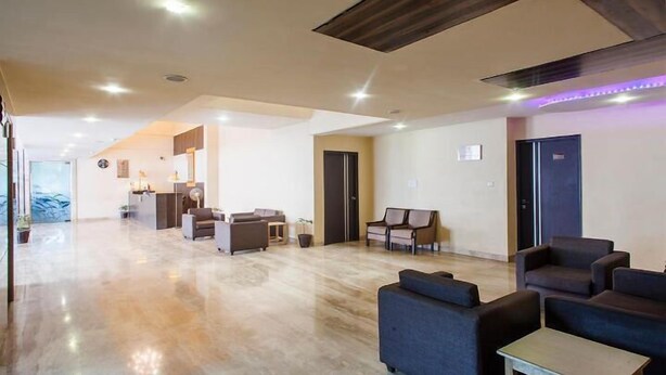 A spacious lobby with a reception desk, seating area, and a modern design with a wooden ceiling and recessed lighting. - Hotel Shubham Majesty (Mathura)