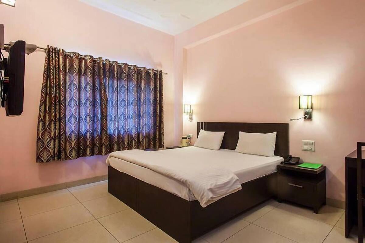 A hotel room with a bed, nightstands, a lamp, and a television.