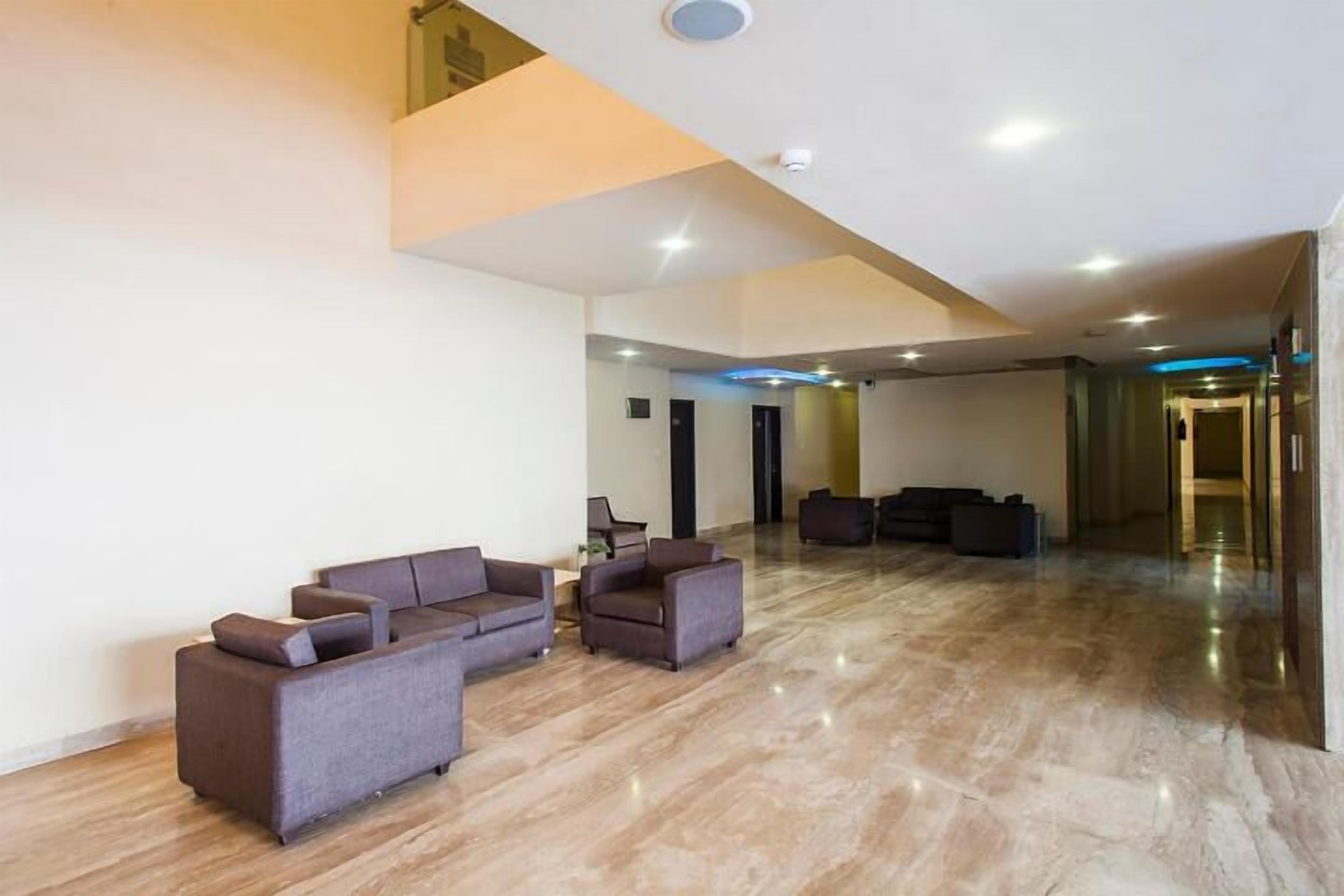 Eine geräumige Lobby mit hoher Decke, Marmorboden und einer Sitzecke mit Sofas und Sesseln.