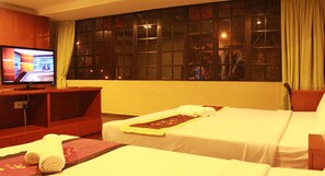 Habitación de hotel con dos camas, televisión y un ventanal grande con cortinas.
