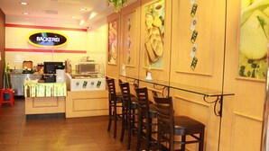 A restaurant interior with a counter, chairs, and wall art. - Your Hotel (Genting Highlands)