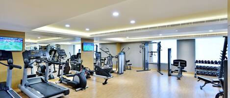 Un gimnasio con cintas de correr, elípticas, máquinas de pesas y mancuernas.
