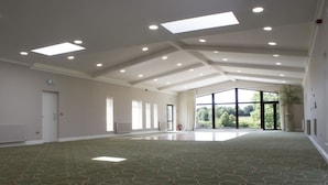 A spacious room with a high ceiling, recessed lighting, large windows, and a patterned carpet. - The International (Knock)