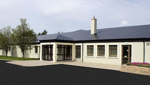 A modern building with a flat roof, large windows, and a covered entrance. - The International (Knock)