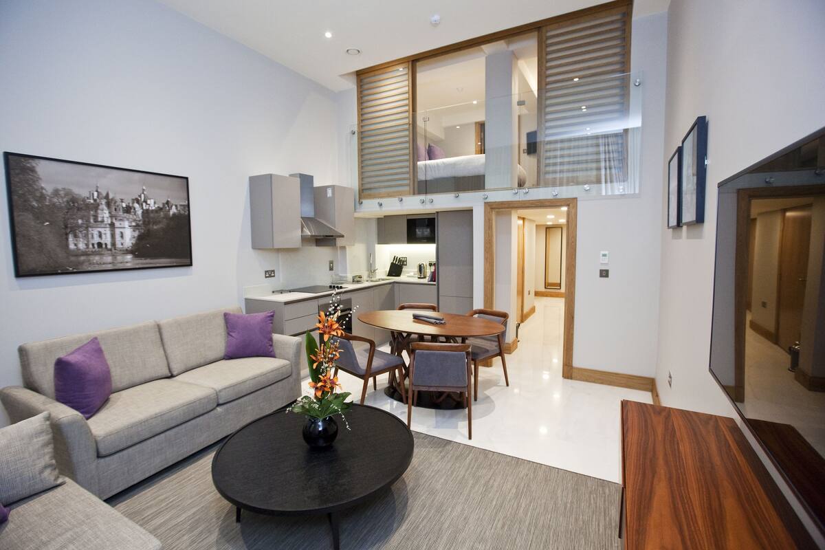 A modern living room with a sofa, coffee table, and dining area.