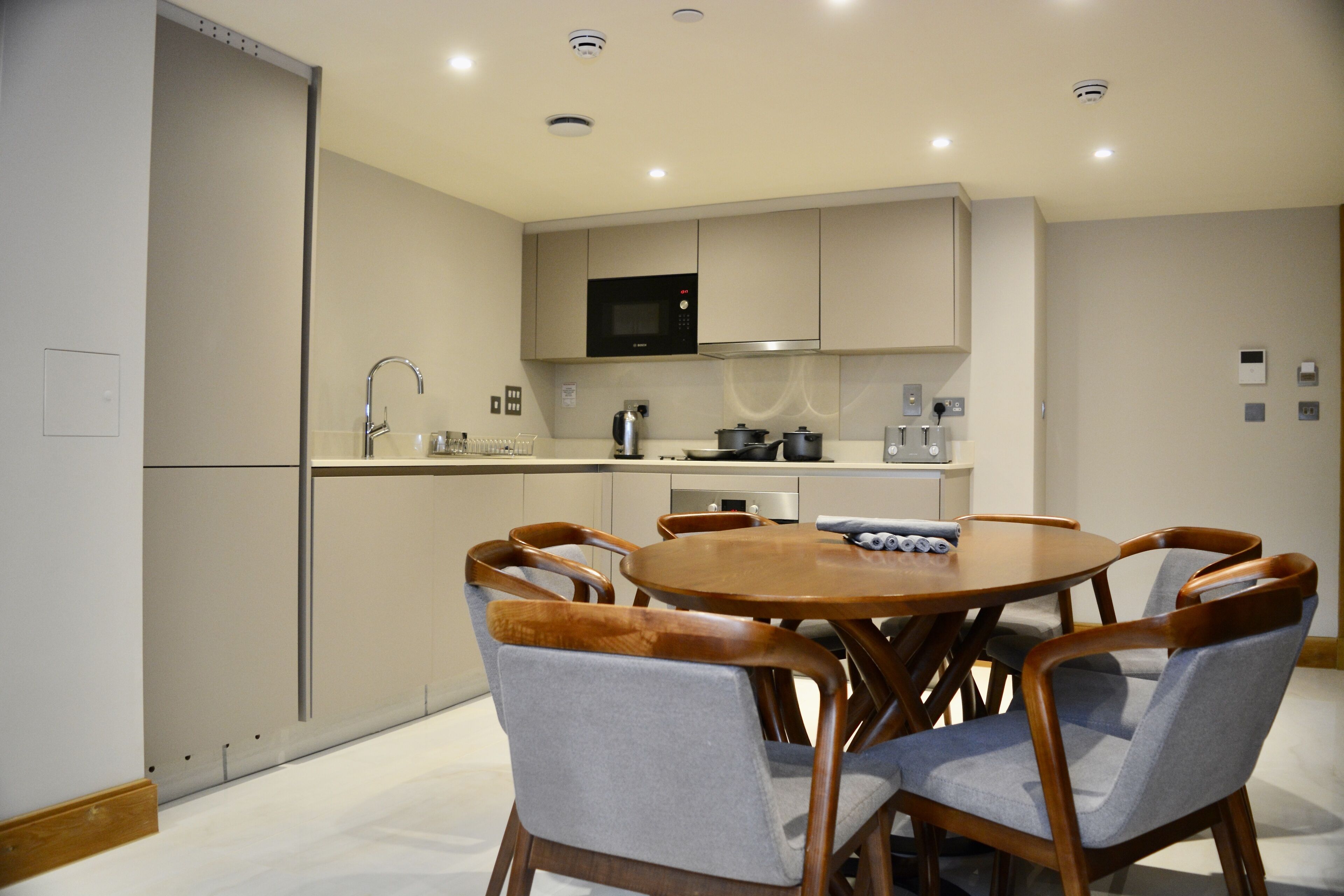 A modern kitchen with a microwave, stove, and sink. There is a dining table with six chairs.