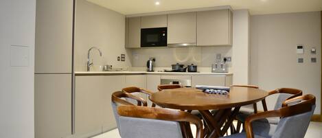 A modern kitchen with a microwave, stove, and sink. There is a dining table with six chairs.