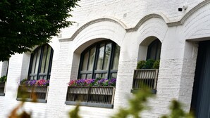 A building with white brick exterior, arched windows, and flower boxes on the windowsills.