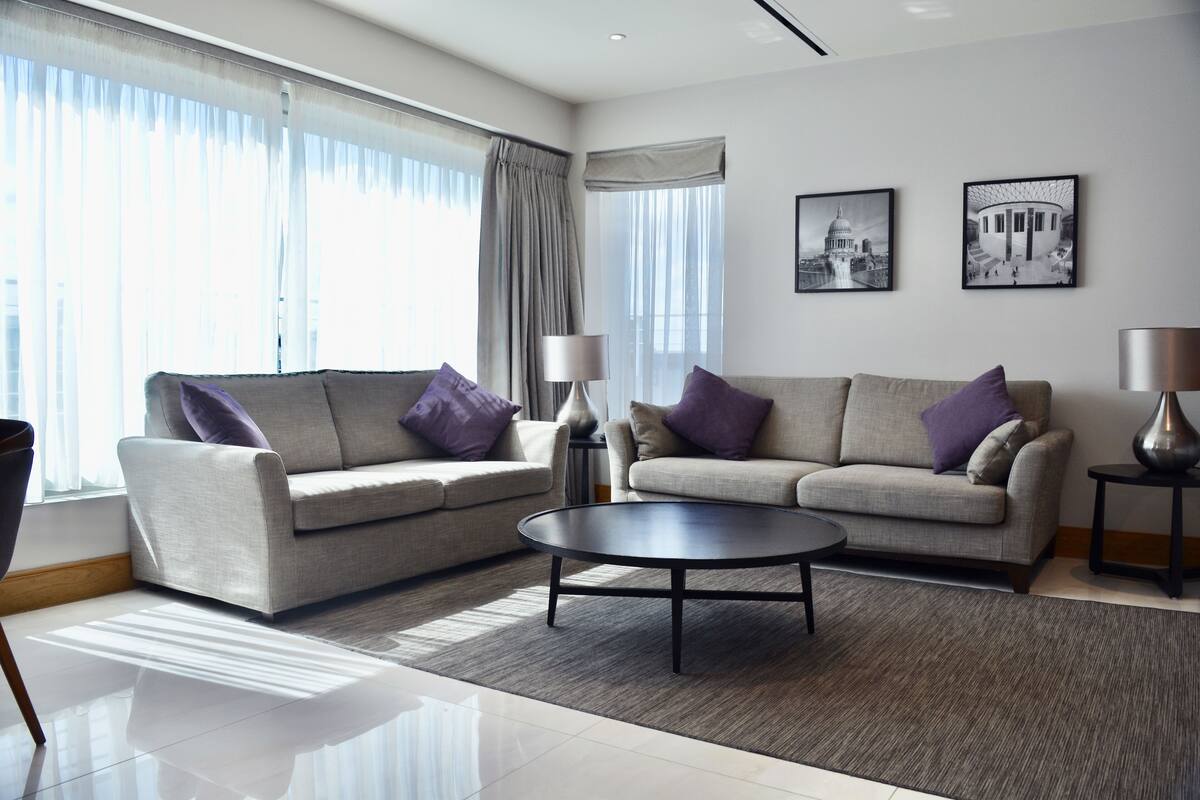 A modern living room with two sofas, a coffee table, and two side tables with lamps.