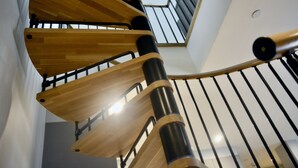 A spiral staircase with wooden steps and black metal railings.