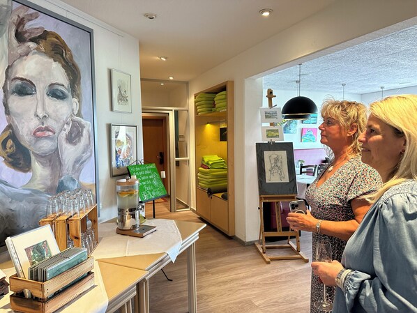 Una galería con pinturas y una mesa mostrando materiales de arte.