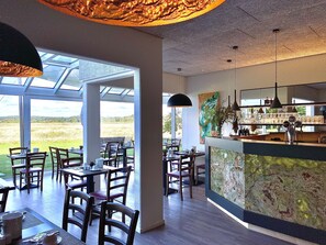Een restaurant met een bar, grote ramen en uitzicht op het landschap.