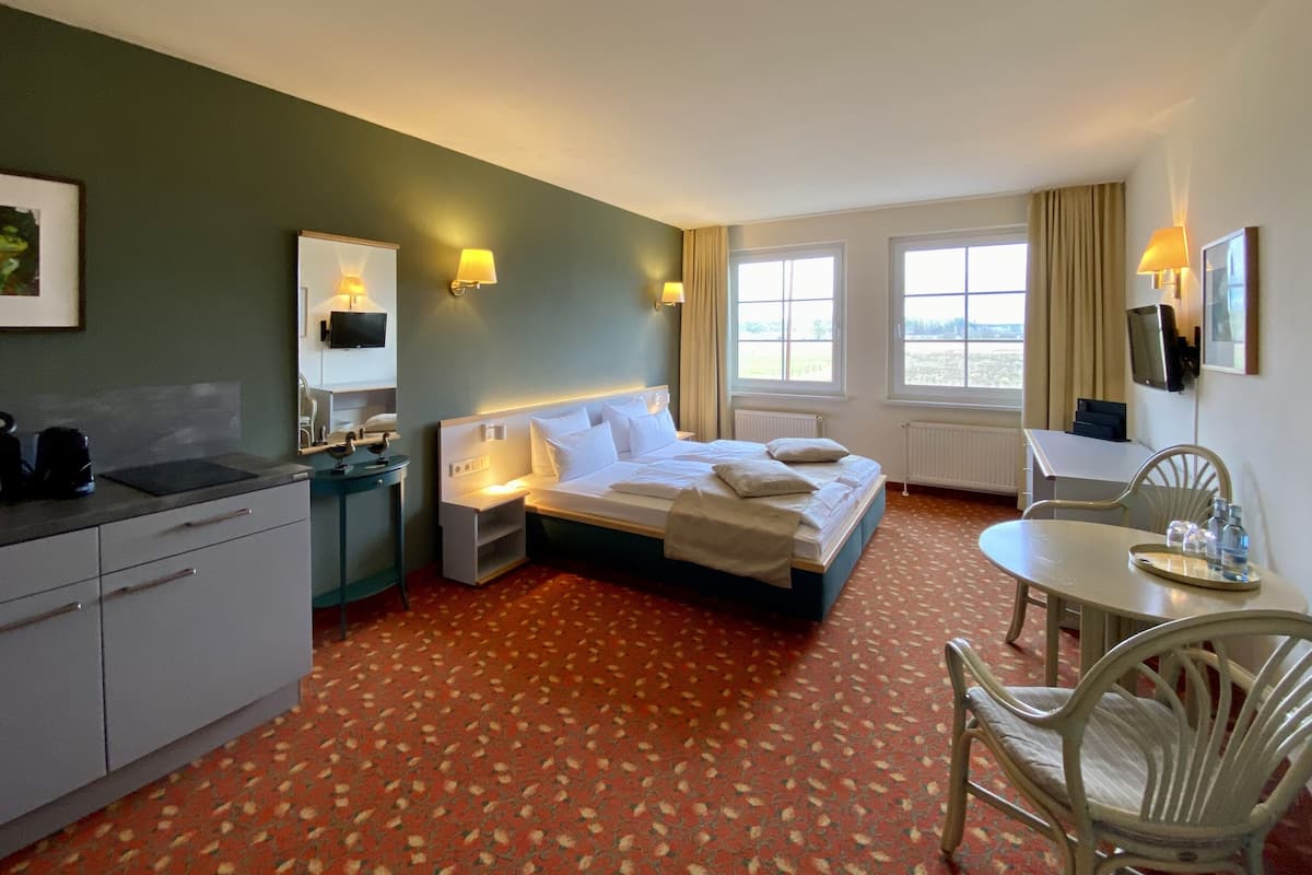Une chambre d’hôtel comprenant un lit, des tables de chevet, un bureau, une chaise et une vue sur l’extérieur par les fenêtres.