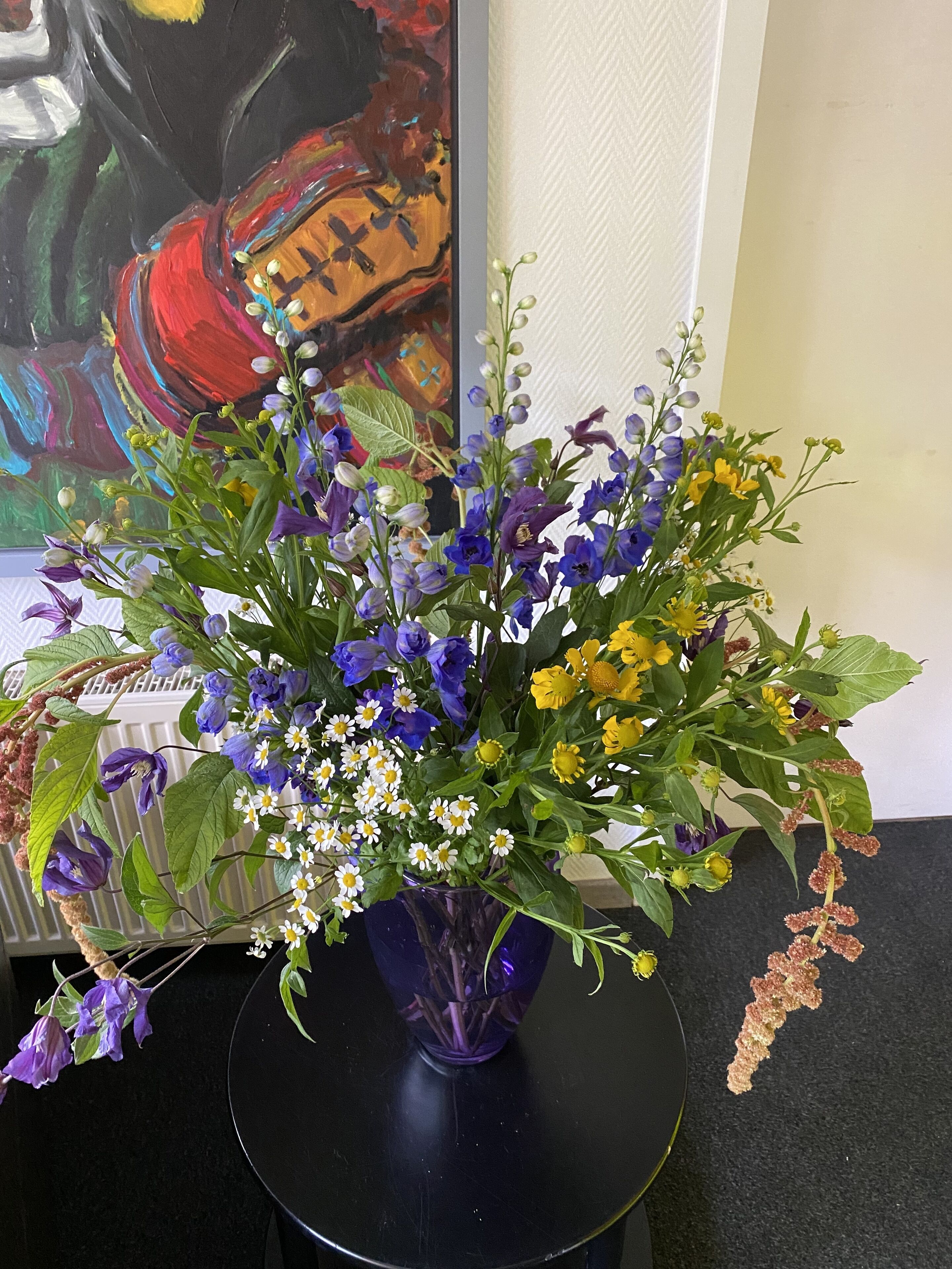 A vase with a variety of flowers on a round table.